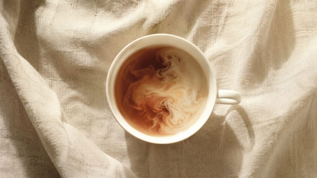 白い布の上でカップに注がれた紅茶とミルク